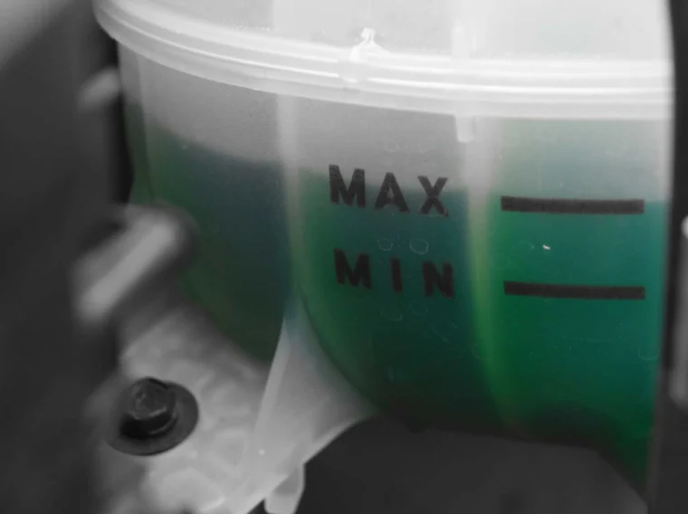 A translucent container partially filled with green fluid, marked with "MAX" and "MIN" level indicators, is often used in Fluid Exchange Services.