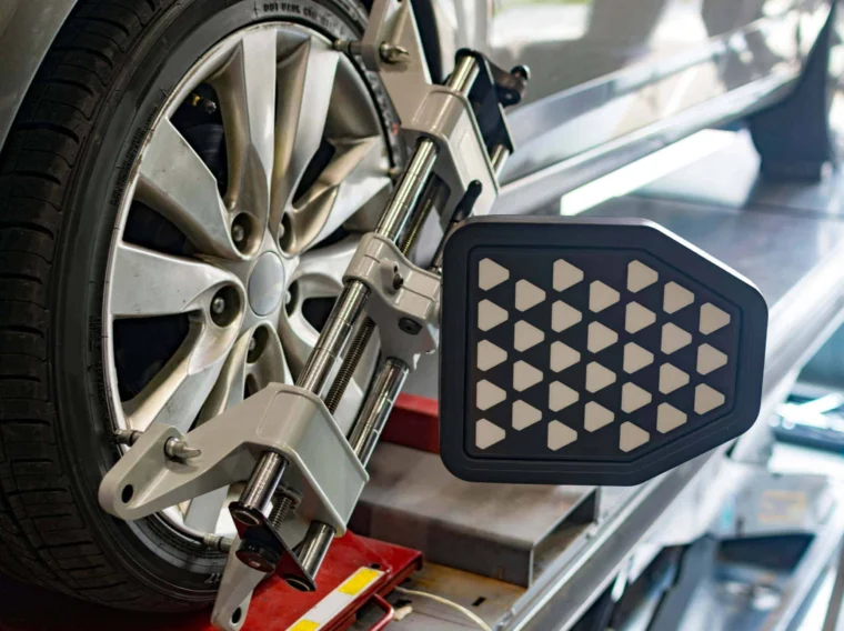 A close-up of a car tire with a wheel alignment tool attached during Alignment Services as part of routine vehicle maintenance.